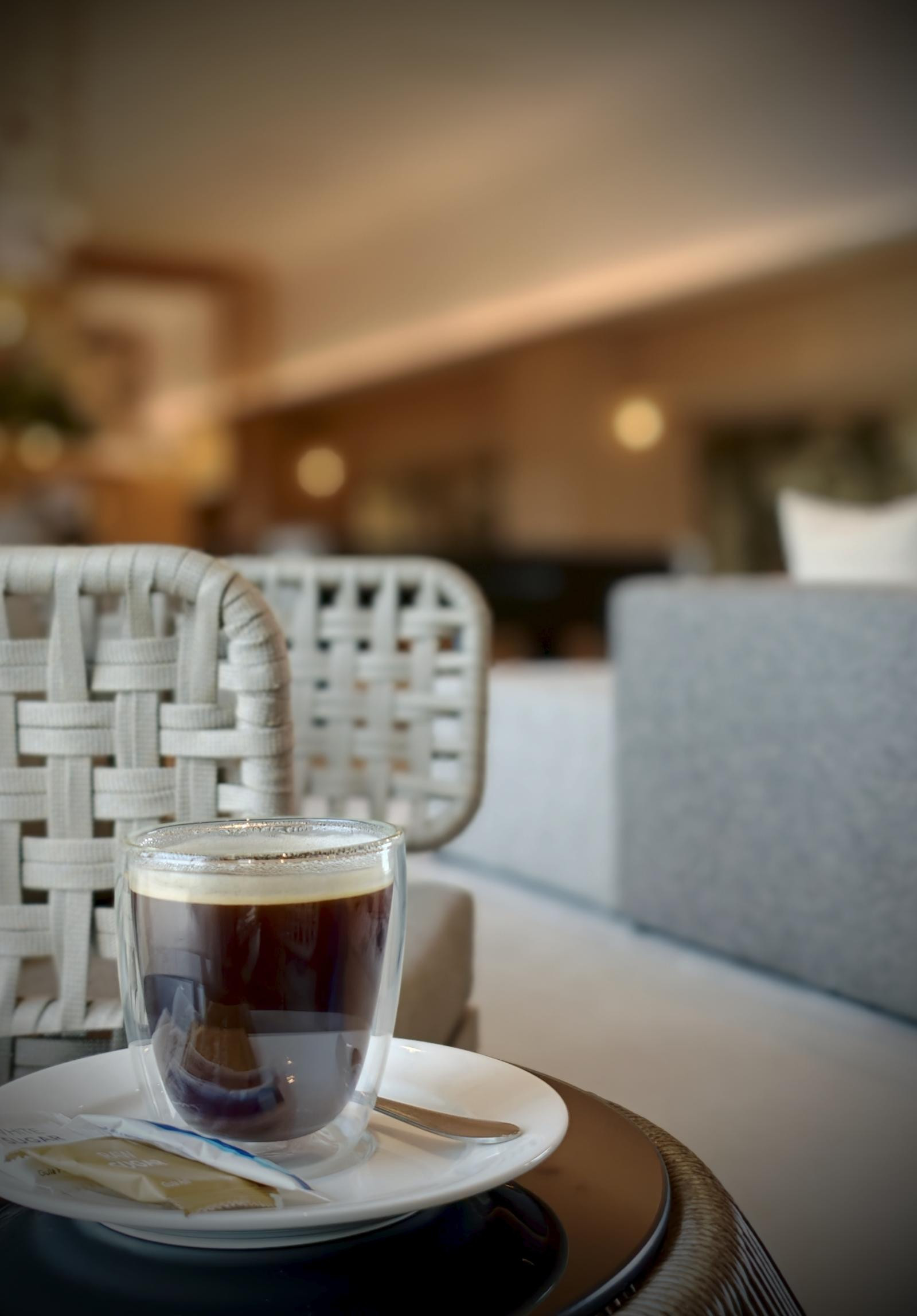 ラウンジのソファ席に置かれたガラスのカップのコーヒー