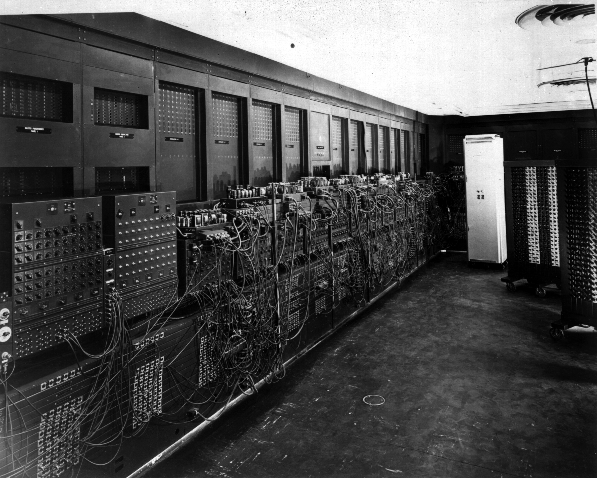 部屋の壁一面に配線と装置が並ぶ、ENIAC