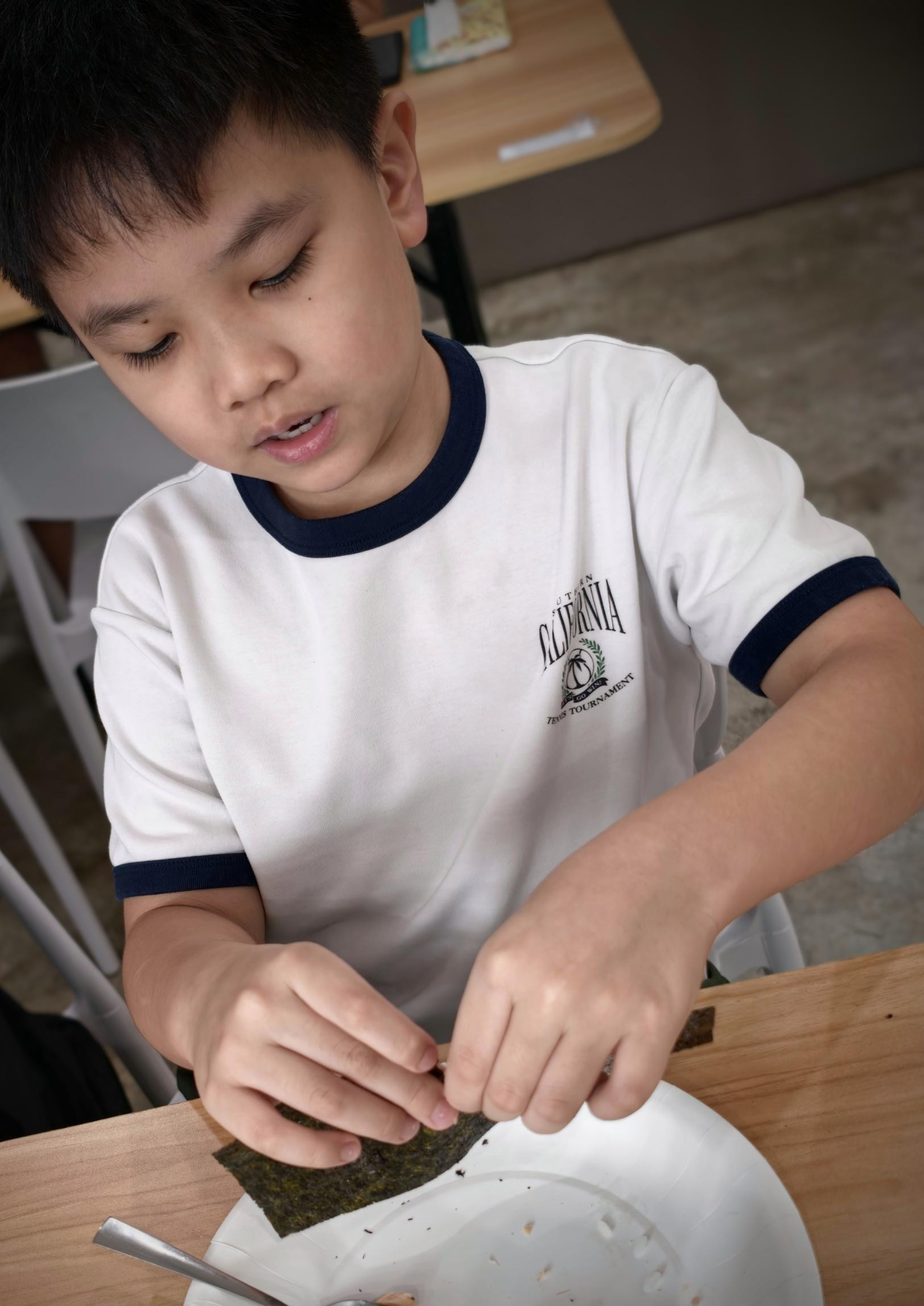 海苔を手に、おにぎりを作る男の子