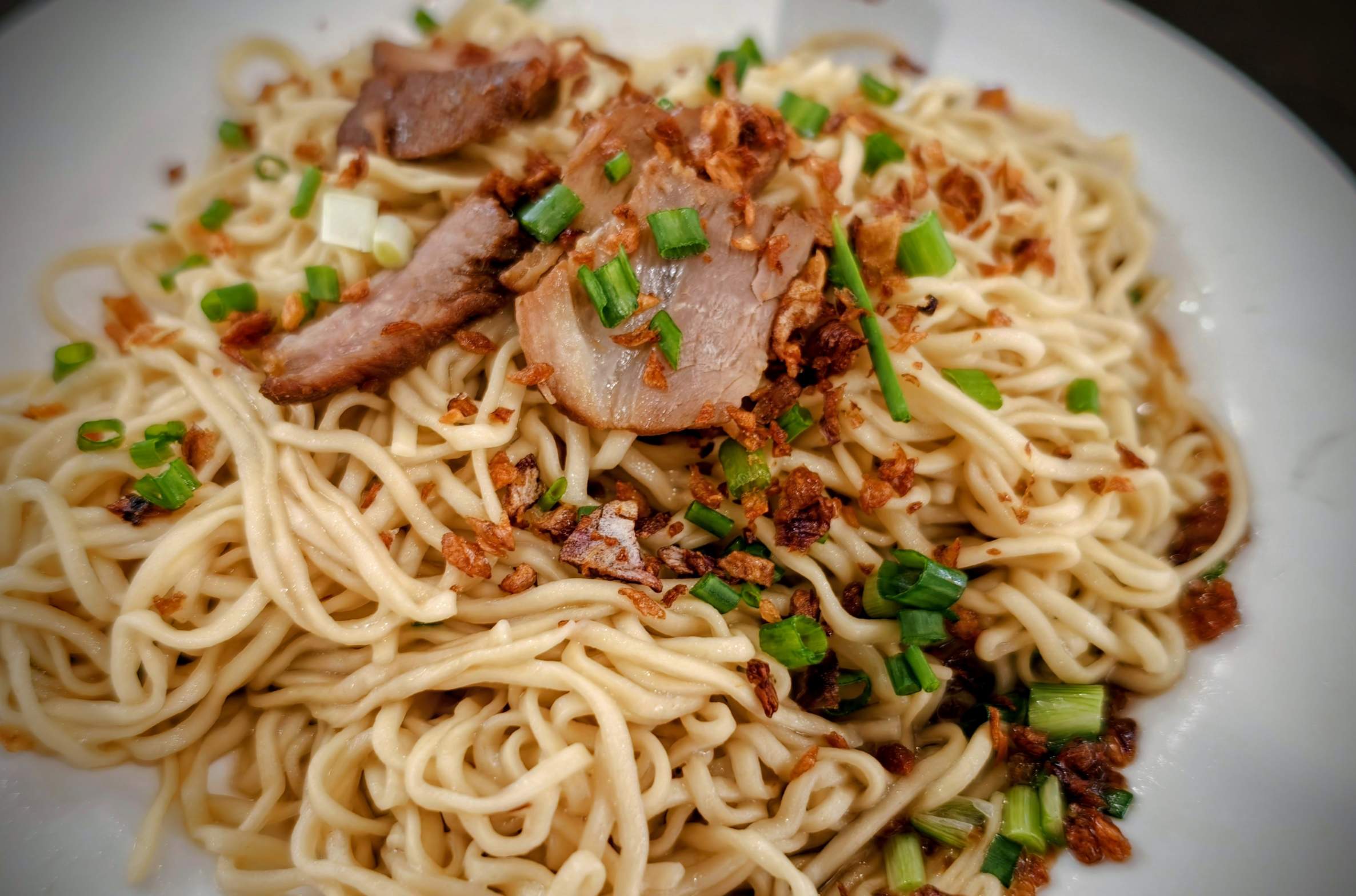 白っぽい細麺にチャーシューと揚げエシャロット、青ねぎをのせたカンプア麺
