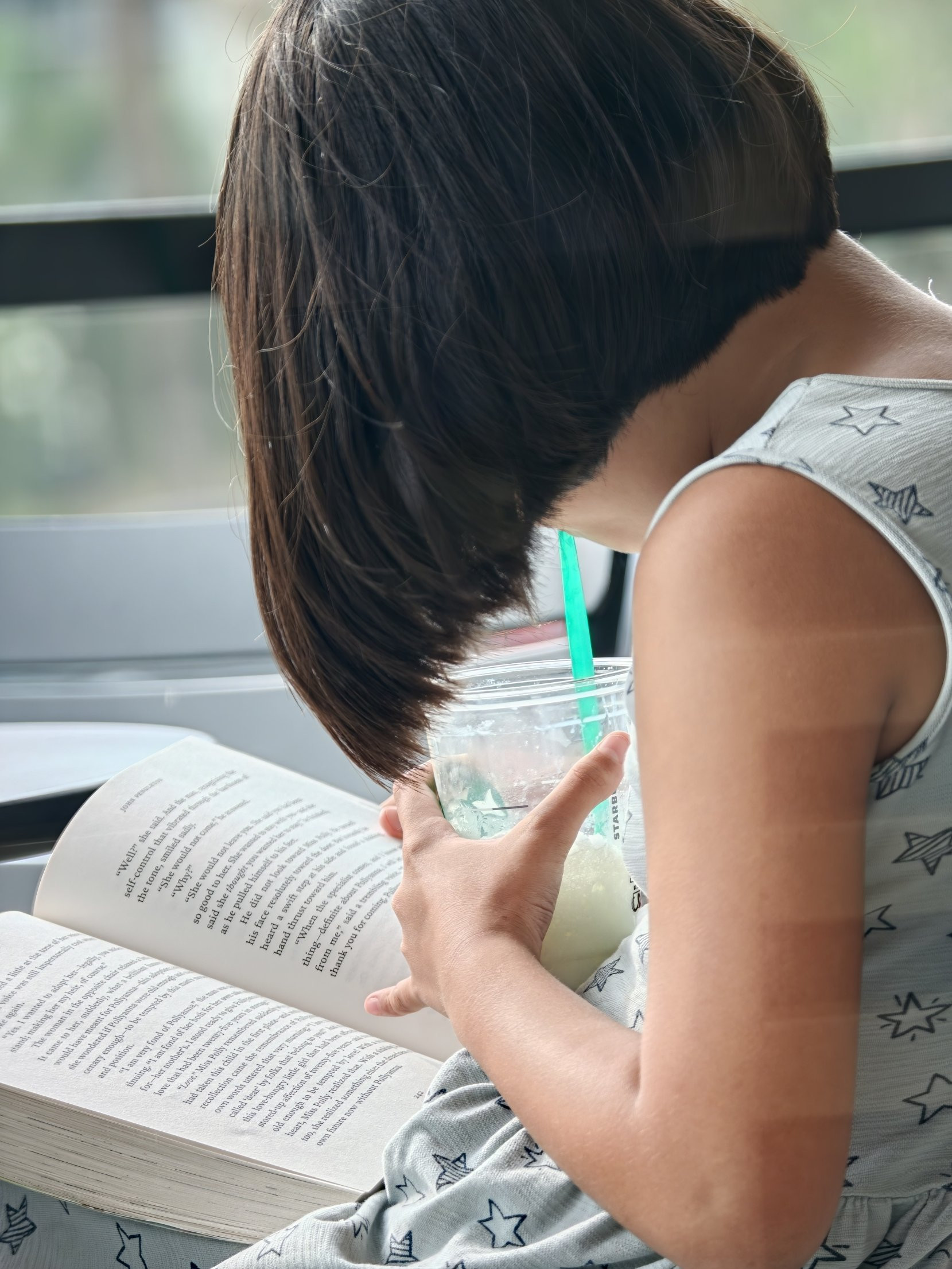 スターバックスのカップを手に、本を読む娘の後ろ姿